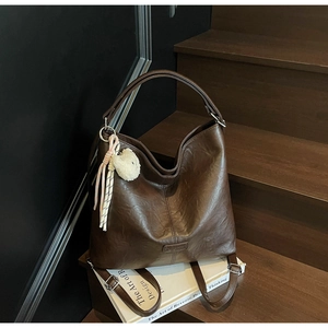 Detail showing the brown faux leather tote texture and a cute white plush bear keychain