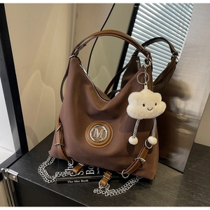 Dettaglio borsa tote marrone impermeabile con logo M argento e ciondolo a nuvola