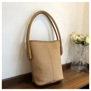 Detail shot of the woven texture and dark brown trim of the bucket shoulder bag