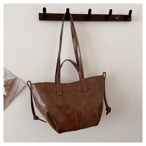 Detailed view of brown faux leather tote bag with retro oil finish on a wooden hanger