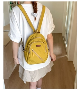 Close-up of the ginger yellow waterproof nylon backpack with front zipper pockets