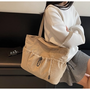 Detail of khaki nylon tote bag featuring front drawstring pockets and water-resistant texture