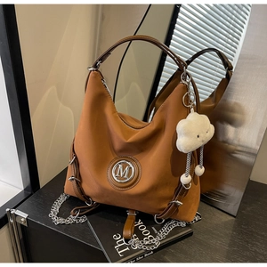 Dettaglio della borsa tote vintage marrone con logo M, catena argento e ciondolo