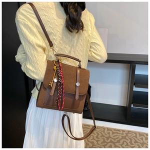 Detail of brown vintage leather backpack with key charm and fringe tassel on female model