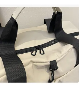Detail view of the smooth dual plastic zippers on a large cream travel bag