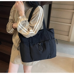 Detail of black nylon tote bag featuring multiple drawstring pockets and utility design