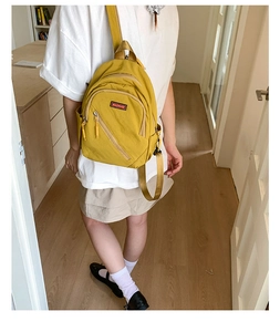 Detailed view of yellow nylon backpack with side pockets and front zip pocket