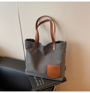 Dettaglio della borsa tote in tela grigia con tasca in pelle marrone ed etichetta