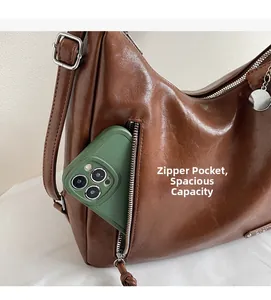 Gros plan du sac en cuir vintage marron montrant une poche zippée verticale pratique