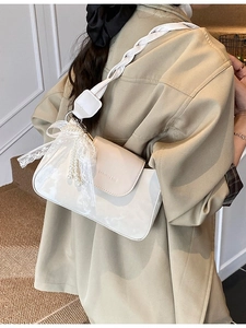 Chic white glossy underarm bag with woven strap and pearl lace bow charm on model