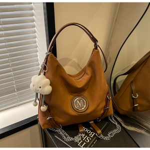 Dettaglio della borsa hobo marrone con logo M in metallo e ciondolo a nuvola soffice