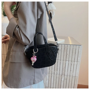 Black leopard print crossbody tote bag with pink heart keychain charm on a model