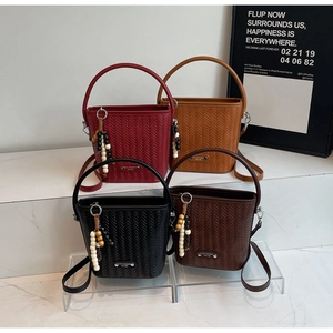 Close-up of four woven bucket bags in vintage red, orange, black and brown colors
