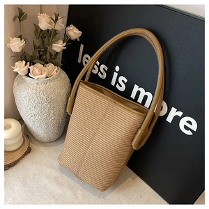 Detail of woven straw bucket bag with leather handles and minimalist home decor setting