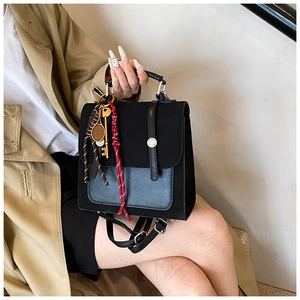 Close-up of black backpack with matte texture, gold hardware, and red pendant details