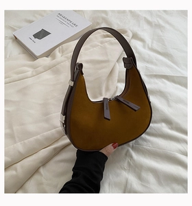 Detailed close-up of a mustard yellow suede hobo bag with contrast dark brown leather trims