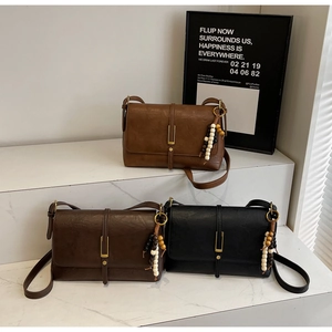 Detail of vintage flap crossbody bags in dark brown and black with beaded charms