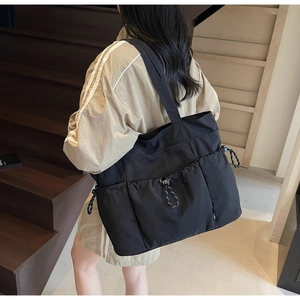 Detail of black nylon tote bag featuring functional drawstring pockets and large capacity