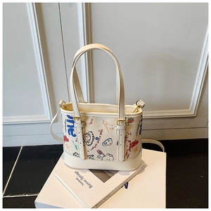 Détail du sac graffiti crème avec lettres bleues et motif de visage de dessin animé
