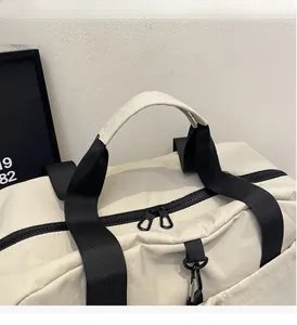 Detail of reinforced handles and smooth double zippers on the cream travel bag