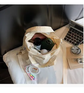 Spacious interior of beige canvas bucket bag holding wallet and phone with long strap