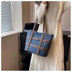 Detail view of denim tote bag with brown leather lattice and gold studs decoration