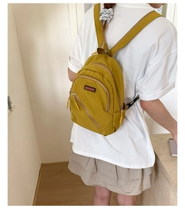 Rear view of a model wearing a stylish ginger yellow nylon backpack for casual travel