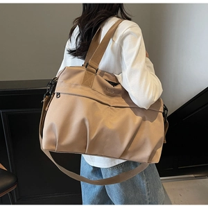 Grande borsa da viaggio kaki indossata come borsa a tracolla in un ambiente moderno