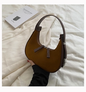 Detail view of brown suede crescent bag with dual zippers and smooth leather strap