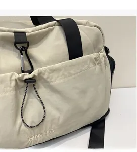 Detailed close-up of soft beige nylon fabric texture and embroidered brand logo on bag