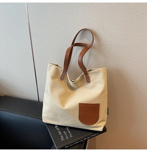 Dettaglio della borsa tote in tela con tasca in ecopelle marrone e il logo A-MANGI
