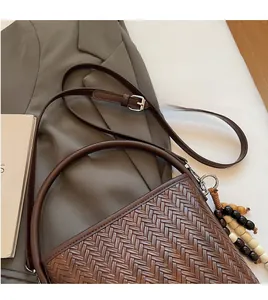 Detail of dark brown woven shoulder bag with wooden beads and adjustable strap
