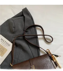 Détail du sac bandoulière vintage marron avec perles en bois et finitions dorées