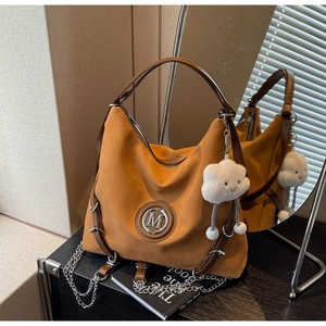 Dettaglio della borsa tote in pelle scamosciata caramello con logo M e charm nuvola morbida