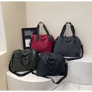 Detail of four large travel duffel bags in red, grey, green, and black on displays
