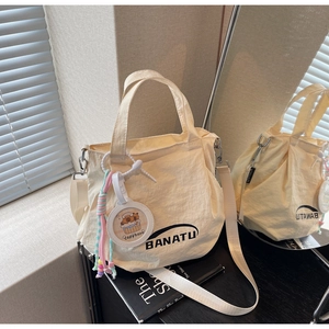 Close-up of cream canvas shoulder bag with BANATU logo and cute Capybara pendant
