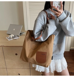 Vista dettagliata della borsa tote in tela marrone con patch in pelle e spallacci robusti