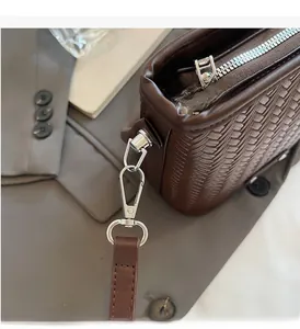 Detailed close-up of brown woven texture handbag with glossy silver metal hardware