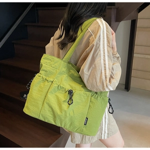 Detail of green nylon tote bag with functional drawstring pockets and shoulder strap
