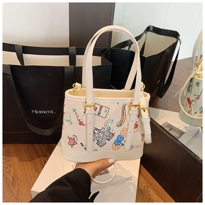 Détail du sac cabas blanc avec motifs graffiti colorés et boucles en métal