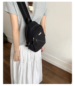 Detail of black nylon chest bag showing waterproof fabric and multiple zipper pockets