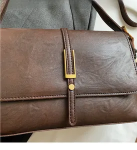 Gros plan sur un sac en cuir marron vintage avec boucles dorées mates et texture fine