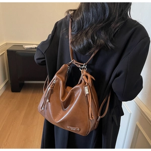 Sac fourre-tout marron vintage en similicuir porté par un mannequin en intérieur