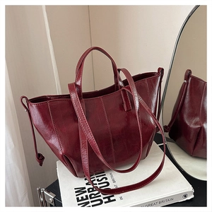 Detail of burgundy patent leather tote bag with vertical stitching and knot drawstring
