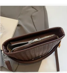 Close-up of smooth metal zipper detail on dark brown woven texture shoulder bag