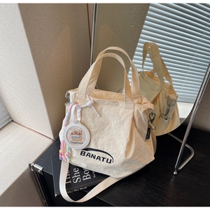 Detail of cream nylon pleated handbag with BANATU logo and cute Capybara charm
