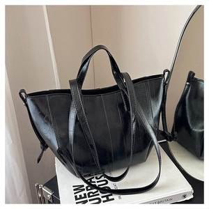 Detail of the glossy black faux leather texture and drawstring on a large tote bag