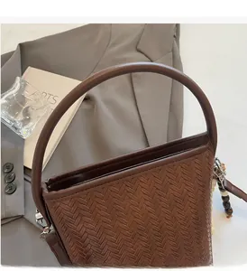 Close-up of deep brown woven bucket bag featuring rigid circular handle and wooden bead detail
