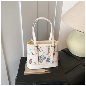 Vue détaillée du sac cabas crème avec graffitis colorés et finitions métalliques dorées