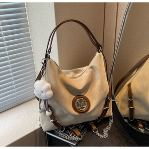 Dettaglio della borsa tote in tela con cinturini in pelle marrone e logo su legno scuro